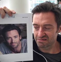 a man holding up a photo of himself in front of the camera with his eyes closed