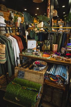 a store filled with lots of clothing and accessories on display in front of a wooden table