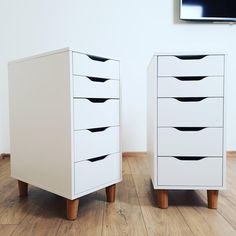 two white drawers sitting next to each other on top of a hard wood floor in front of a flat screen tv