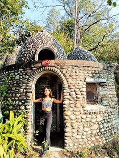 a woman standing in front of an outdoor stone oven with two large pots on top