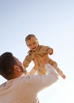 a man holding a baby up in the air