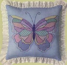 a blue and white pillow with a pink butterfly on the front, sitting on a green wall