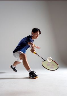 a young man holding a tennis racquet on top of a white floor