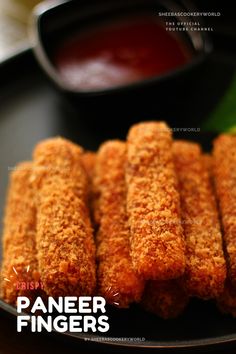 some fried food on a black plate with dipping sauce in the backgroung