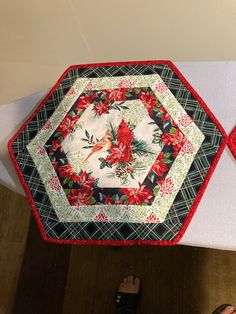 someone is standing on the floor next to a quilted table runner with poinsettis