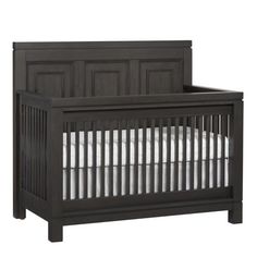 a black crib with white sheets on the bottom and side rails, in front of a