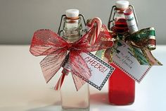 two glass bottles with candy canes in them and tags attached to the top, sitting on a table