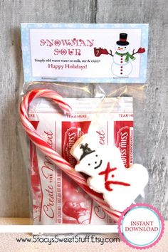 a candy cane with a snowman on it next to a bag of holiday treats