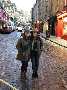 two women standing in the middle of a cobblestone street