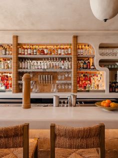 an empty bar with chairs and bottles on the wall behind it, in front of a row of liquor bottles