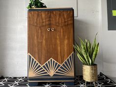 a wooden cabinet sitting on top of a black and white rug next to a potted plant