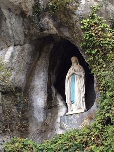 a statue in the middle of a cave with ivy growing around it's sides