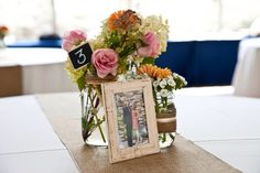 the table is set with flowers and a photo frame on top of it, as well as a sign that says 3