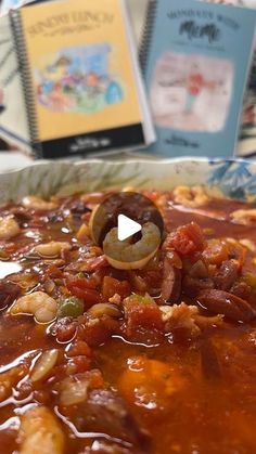 a bowl filled with food sitting on top of a table next to two book's