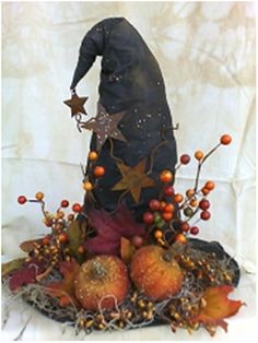 a witches hat sitting on top of pumpkins and berries