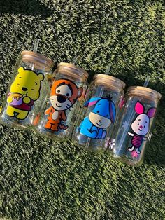 four winnie the pooh tumblers sitting on top of grass