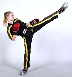 a woman in black and yellow uniform kicking a kick