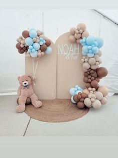 a teddy bear sitting in front of a balloon arch