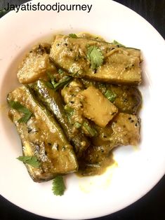 a white plate topped with meat covered in sauce and garnished with cilantro