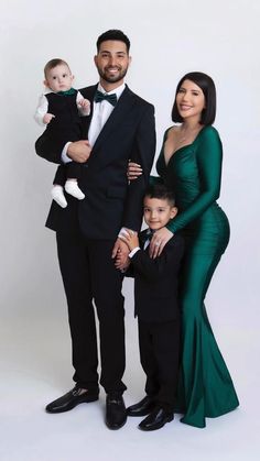 a man in a tuxedo poses with two women and a young boy, both holding a baby