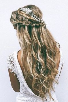 the back of a woman's head with long, wavy hair and flowers in her hair