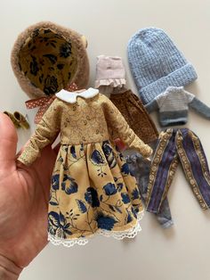 a hand holding a small doll with several different clothes on it's body and hands