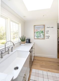 a kitchen with two sinks and a large window in the back ground, along with a rug on the floor