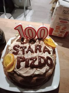 a birthday cake with the number 100 on it is sitting on a table next to a package of milk