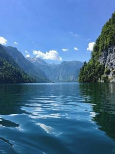 the water is calm and blue with mountains in the background