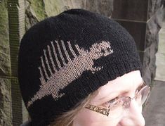 a woman wearing glasses and a black knitted hat with a fish bone on it