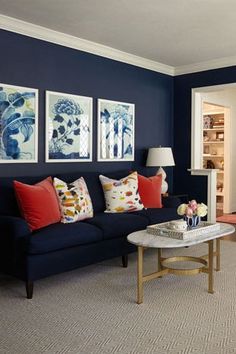 a living room with blue walls and red pillows on the couches in front of them