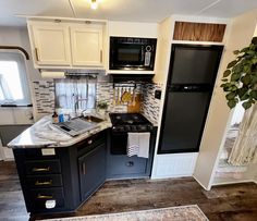 a kitchen with black and white cabinets, marble counter tops and an area rug on the floor