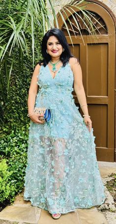 a woman standing in front of a door wearing a blue dress and holding a purse