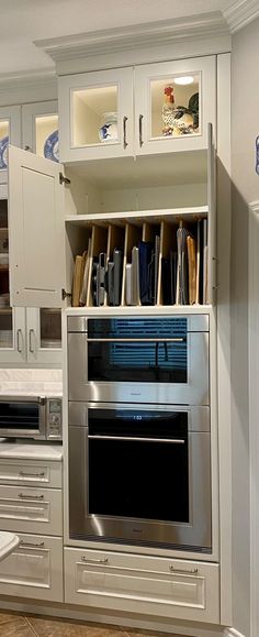 an oven built into the side of a wall in a kitchen with white cabinets and drawers