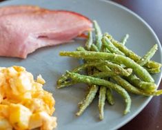 a plate with eggs, green beans and ham on it