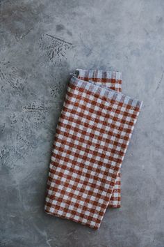 two brown and white checkered napkins sitting on top of a cement floor next to each other