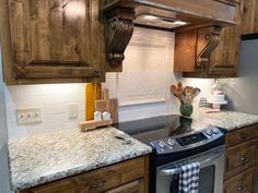 a kitchen with granite counter tops and wooden cabinets, an oven hood over the stove