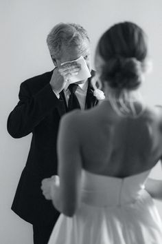 a man in a tuxedo is looking at his bride's eyes as she wipes her nose