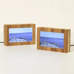 two small wooden frames sitting next to each other on a white surface with blue water in the background