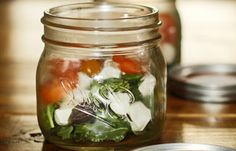 a jar filled with vegetables sitting on top of a wooden table