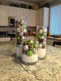 three glass vases filled with ornaments on top of a kitchen counter covered in snow