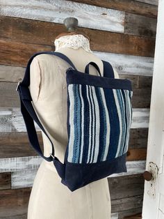 Genuine African indigo cloth and deep navy waxed canvas combine to create a unique, one of a kind backpack. It features a blue striped cotton ticking lining, with a 2 sectioned interior pocket for smaller items, and a zippered top to keep everything secure. The comfy 1 & 1/2 inch wide navy cotton web straps extend to 29 inches with chrome hardware and an 8 inch loop in between. It measures 12 inches tall, 11 inches wide, and 2 inches deep. Perfect for school, work, weekend errands, or travel. This multi blue/cream striped textured indigo cloth is truly a unique piece.  Variations in pattern and minor imperfections should be expected, as authentic indigo cloth is individually hand spun, hand woven, and hand dyed.  These unique attributes add distinct personality and charm.  Waxed canvas onl Blue Cotton Backpack For Travel, Blue Cotton Backpack For Daily Use, Blue Cotton Standard Backpack, Blue Cotton Backpack For Everyday Use, Blue Canvas Standard Backpack, Cloth Backpack, Indigo Cloth, Santa Pillow, Waxed Canvas Backpack