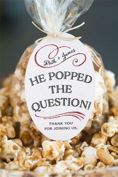 a bag filled with popcorn sitting on top of a wooden table next to a sign that reads he popped the question thank you for joining us