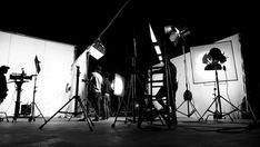 black and white photograph of photographer in front of photography studio lighting equipment set up for photo shoot