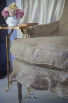 a close up of a chair with a flower vase on the table next to it