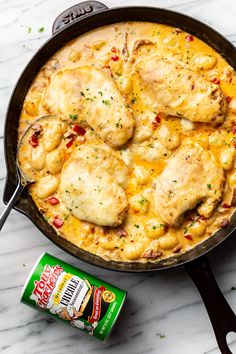 a skillet filled with chicken and cheese next to a can of cheesy sauce