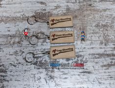 three keychains with cartoon characters on them sitting next to each other in front of a wooden background