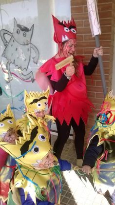 three people dressed up in costumes with masks on their faces and one holding a stick