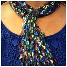 a woman wearing a blue top and a multicolored neck tie with beads on it