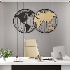 two metal world globes on the wall above a desk